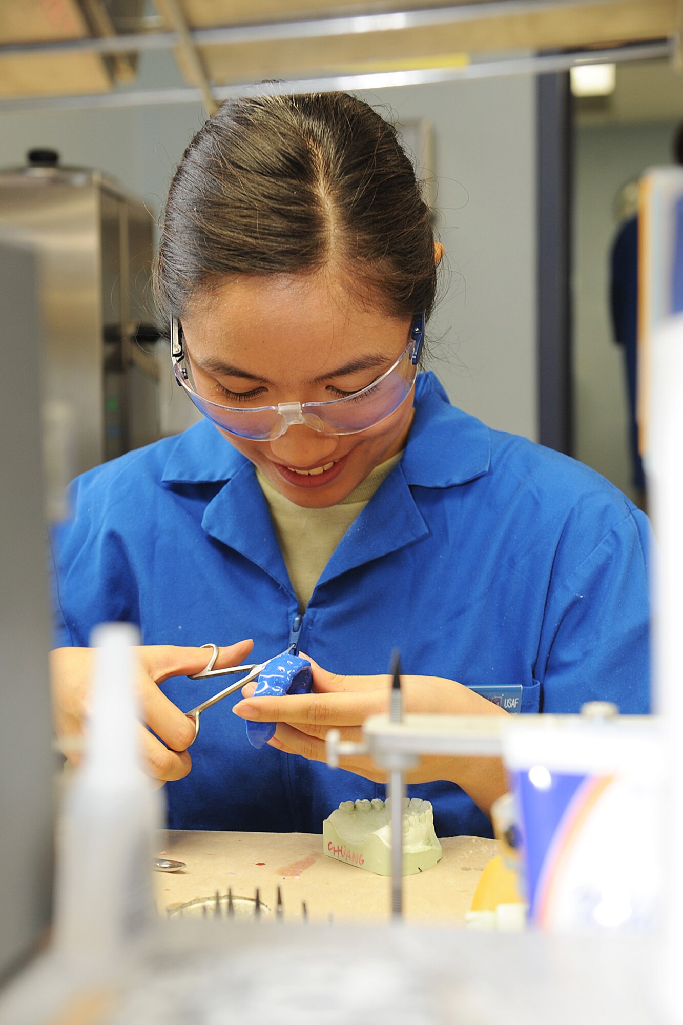 Senior Airman Jorgette Chuang trims the excess plastic from a mouth guard at Scott Air Force Base, Ill., Feb. 19, 2014.  When the plastic is first melted onto the dental cast, there is extra material that needs to be discarded.  Once that process is complete, it is ready to be worn by the patient.  Chuang is a 375th Dental Squadron dental laboratory technician.  (U.S. Air Force photo by Staff Sgt. Maria Bowman)