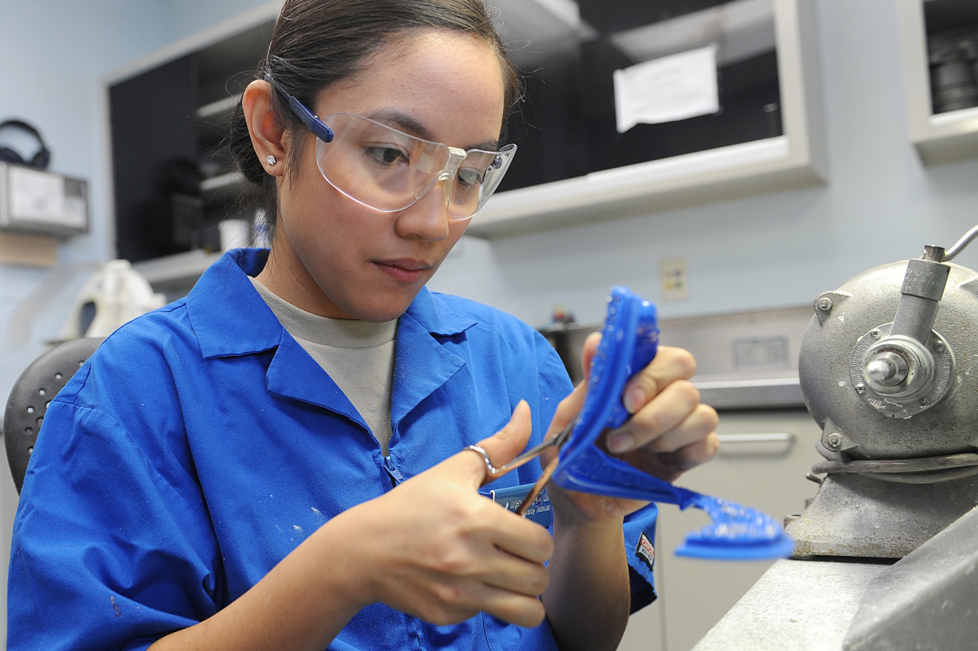 Senior Airman Jorgette Chuang trims the excess plastic from a mouth guard at Scott Air Force Base, Ill., Feb. 19, 2014.  When the plastic is first melted onto the dental cast, there is extra material that needs to be discarded.  Once that process is complete, it is ready to be worn by the patient.    Chuang is a 375th Dental Squadron dental laboratory technician.  (U.S. Air Force photo by Staff Sgt. Maria Bowman)
