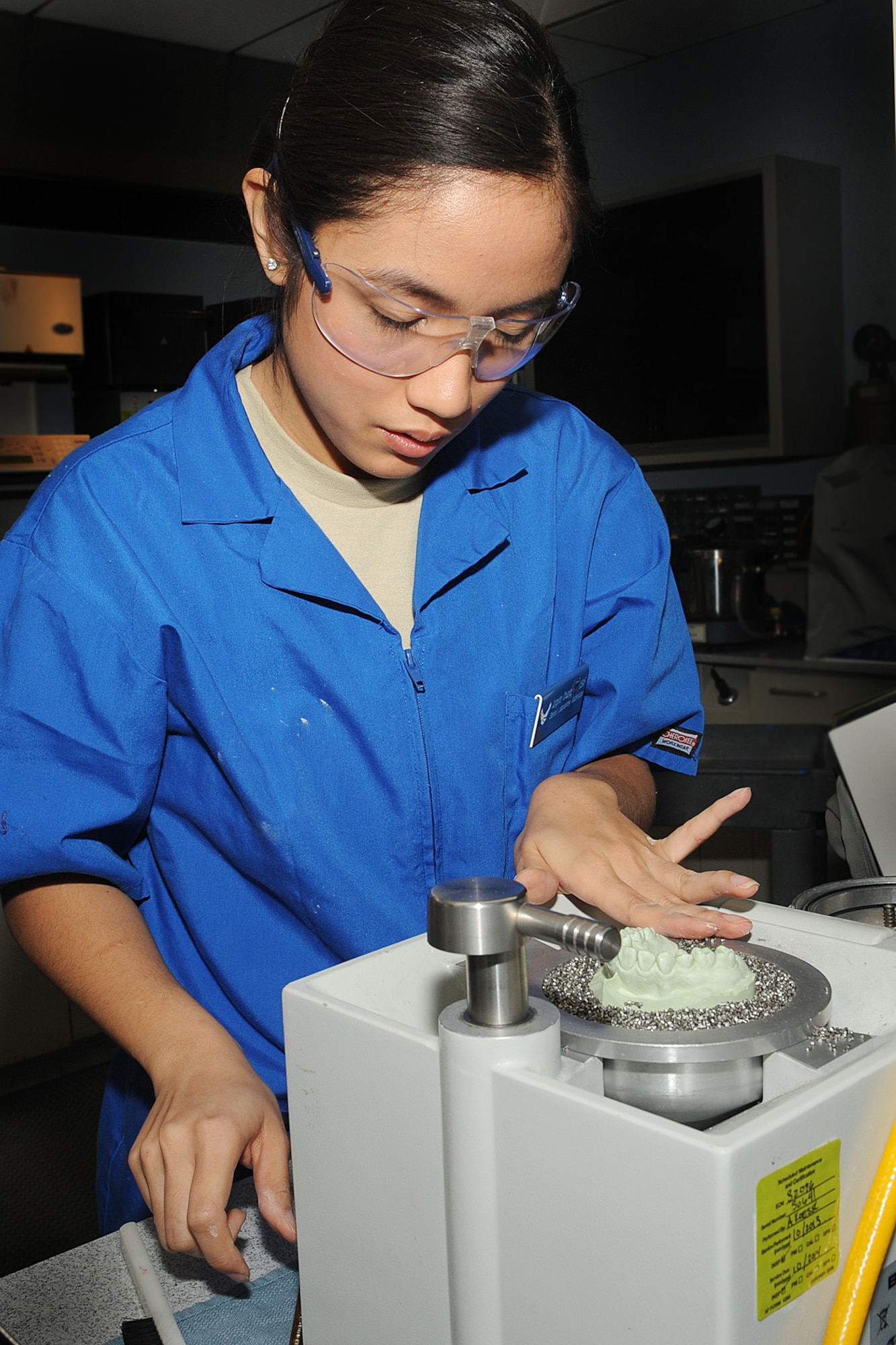Senior Airman Jorgette Chuang prepares a cast using a vacuum former, a machine used to shape a variety of plastics to a mold, at Scott Air Force Base, Ill., Feb. 19, 2014.  This exposes the areas where she wants the mouth guard material to mold around.  As the machine heats up, it melts the plastic around the cast, forming the desired shape.  Chuang is a 375th Dental Squadron dental laboratory technician.  (U.S. Air Force photo by Staff Sgt. Maria Bowman)