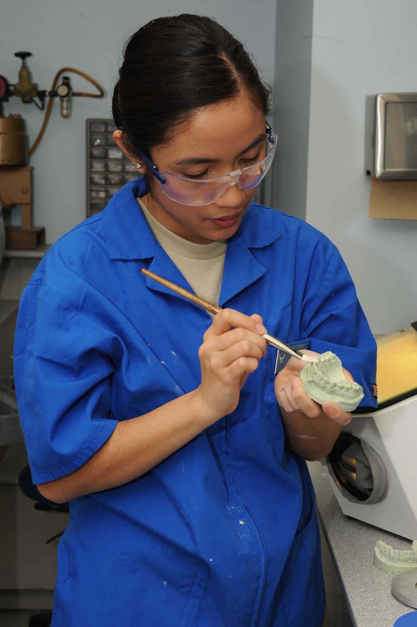 Senior Airman Jorgette Chuang brushes off loose bits of stone from a dental impression at Scott Air Force Base, Ill., Feb. 19, 2014.  The dental impression will be used to make a cast, which can be used to make dentures, crowns or other prostheses.  Chuang is a 375th Dental Squadron dental laboratory technician.  (U.S. Air Force photo by Staff Sgt. Maria Bowman)