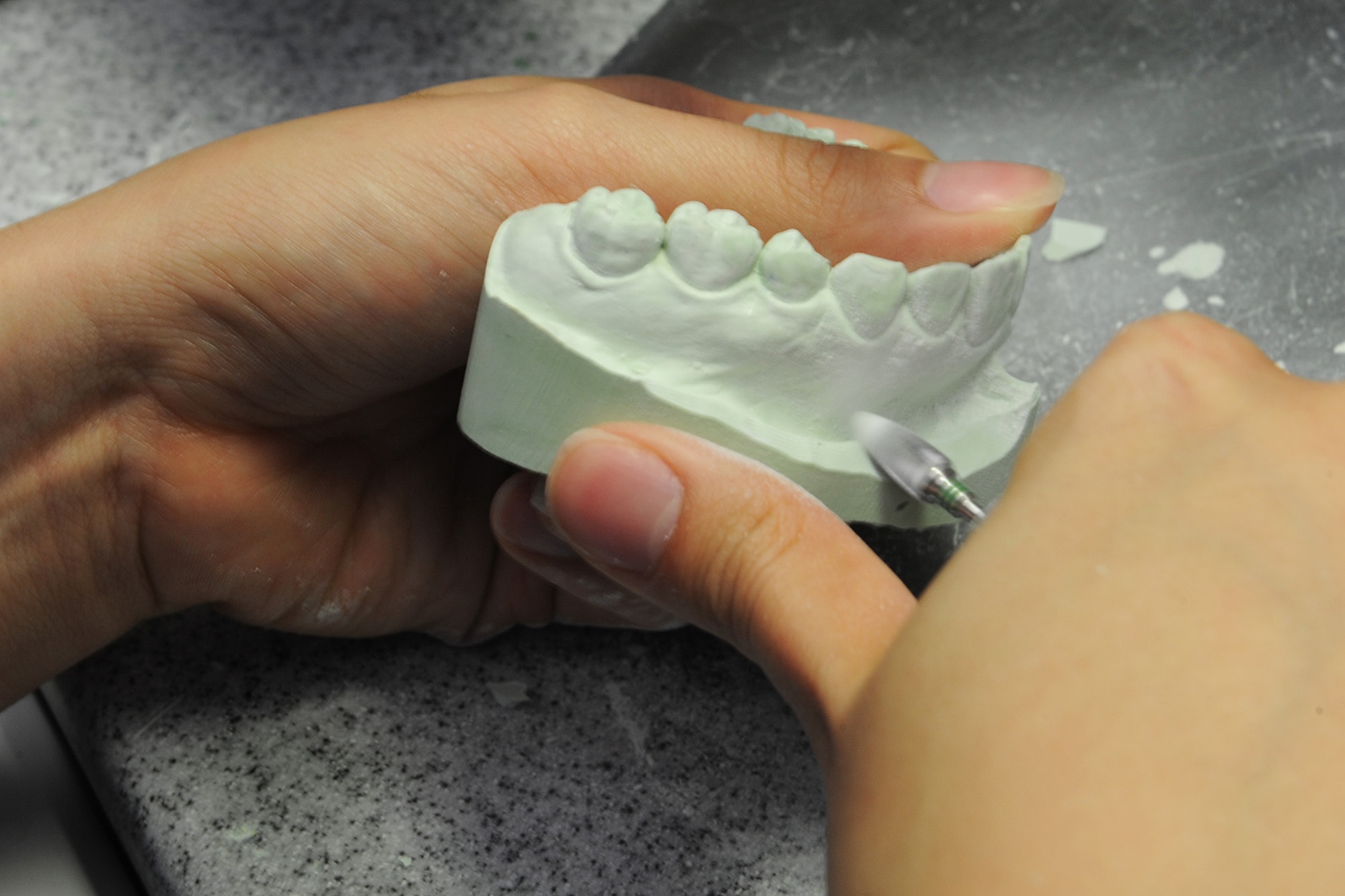Senior Airman Jorgette Chuang grinds the side of a dental cast at Scott Air Force Base, Ill., Feb. 19, 2014.  This process makes room on the side for the mouth guard material to be able to adapt better to the stone.  Mouth guards help protect a person’s teeth during sports or recreational activities that might cause injuries to the mouth.  Chuang is a 375th Dental Squadron dental laboratory technician.  (U.S. Air Force photo by Staff Sgt. Maria Bowman)