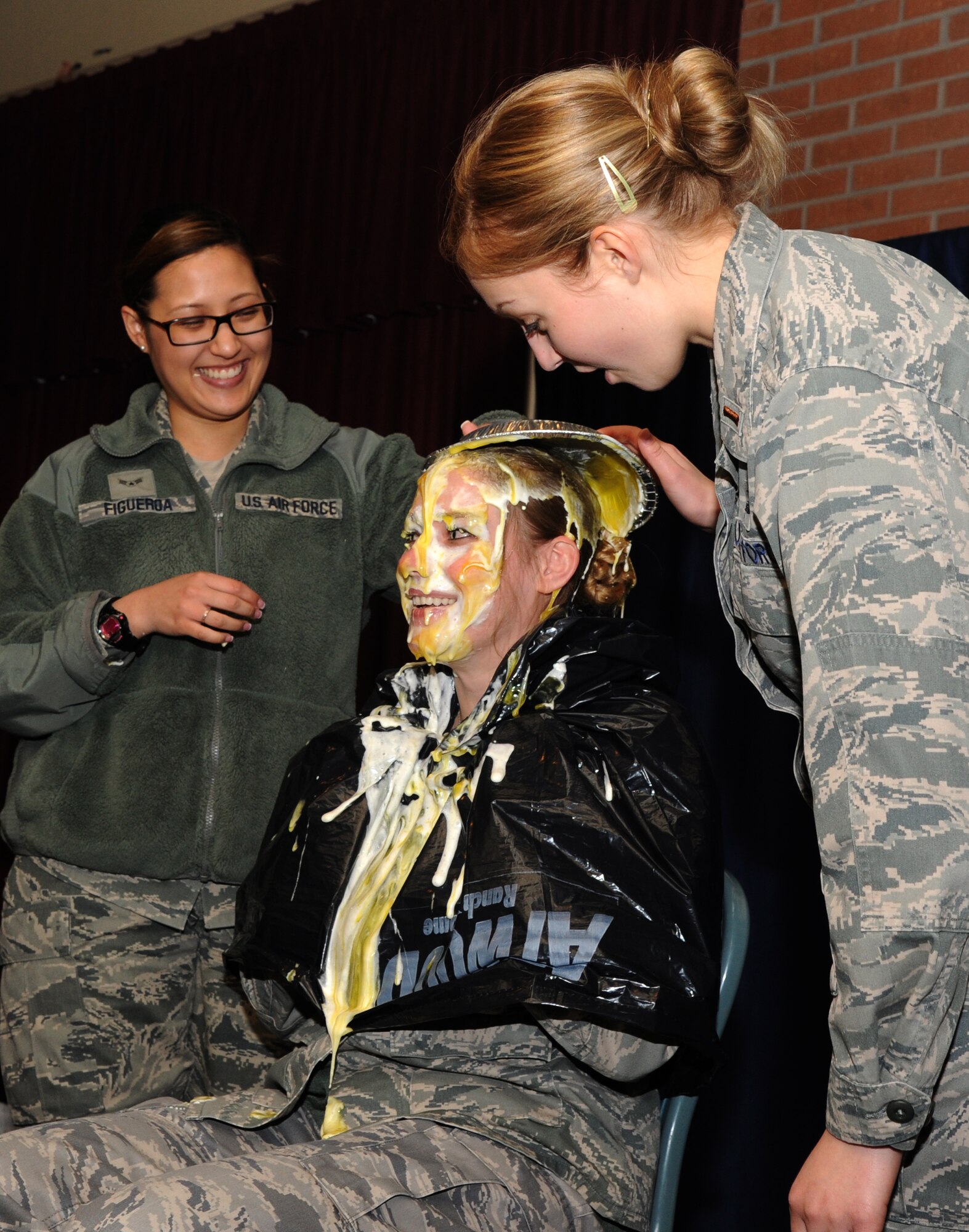 VANCE AIR FORCE BASE, Okla. – Airman 1st Class Shalimar Figueroa and 2nd Lt. Kathrine Thompson pie Capt. Ashley Swansiger March 26 at the Vance Collocated Club. The “Pie in the Eye” fundraiser brought in $817.75 for the 2014 Air Force Assistance Fund Campaign. The pies were purchased with votes and Swansiger took third place with 280. (U.S. Air Force photo/Staff Sgt. James Bolinger)