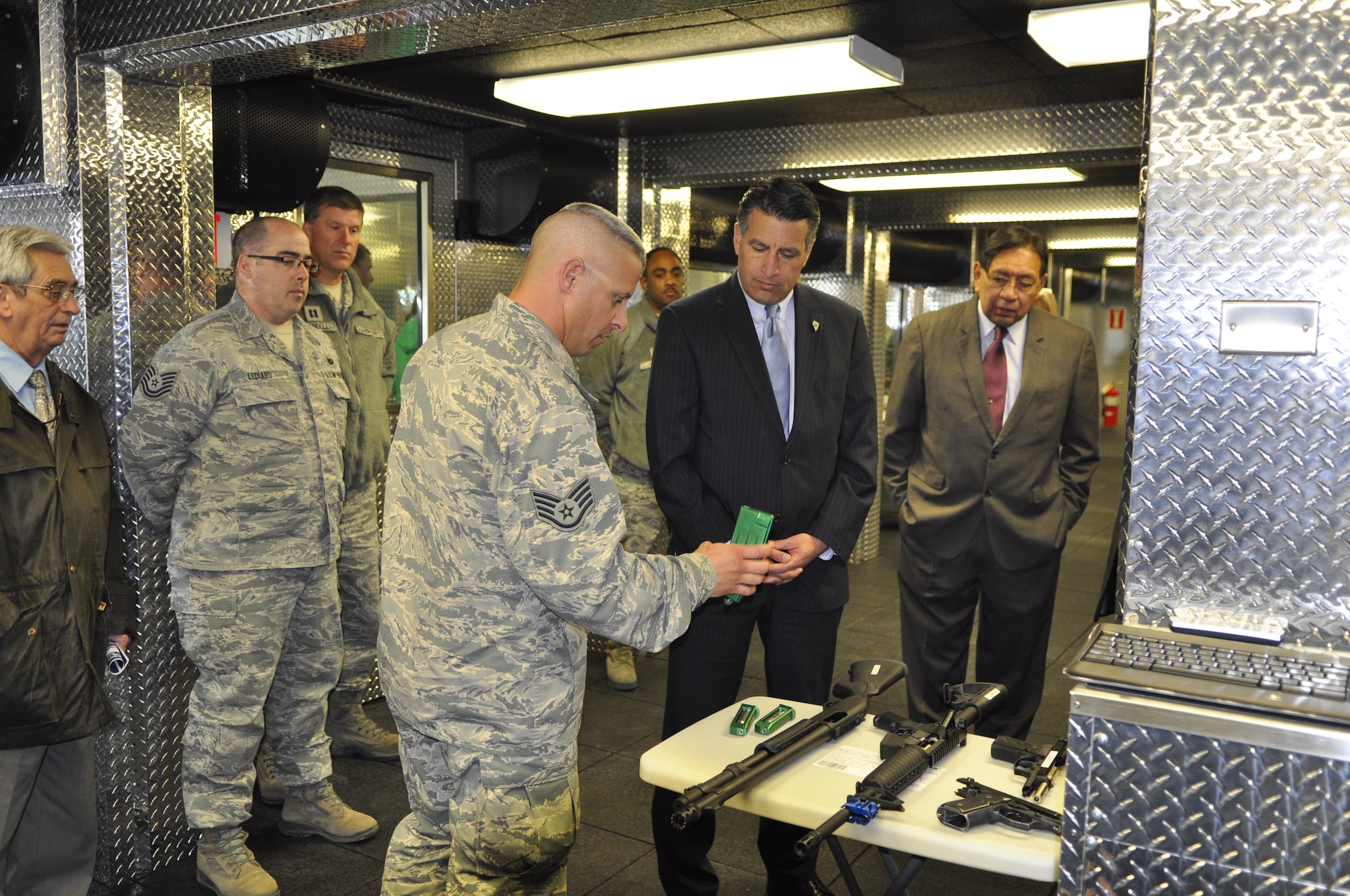 Staff Sgt. Anthony Haley, left, explains the use of a compressed-air powered rifle magazine to Nevada Gov. Brian Sandoval, center, while Reno-Sparks Indian Colony Chairman Arlan Melendez looks on following the opening of the Nevada Air Guard’s Modular Containerized Small Arms Training Set on Tuesday in Reno.

Photo by Master Sgt. Paula Macomber, 152nd Airlift Wing Public Affairs (RELEASED).
