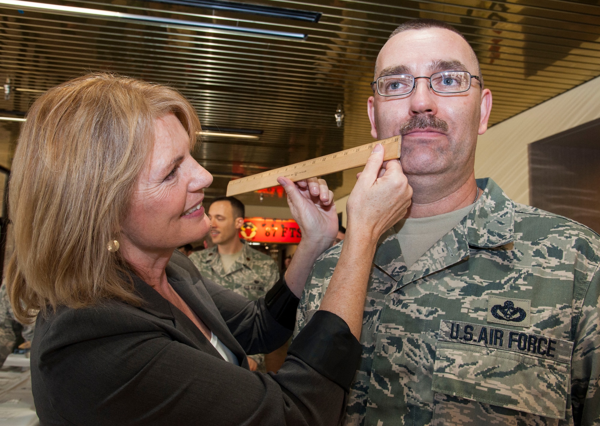 Christina Olds, daughter of retired Brig. Gen. Robin “Ace” Olds, measures the mustache of Chief Master Sgt. Garry Berry, 47th Flying Training Wing command chief at Anderson Hall on Laughlin AFB, Texas, March 28, 2014. Olds was a guest judge at Laughlin’s best and worst mustache contest, after the contest she spoke about her book "Fighter Pilot, the Memoirs of Legendary Ace Robin Olds." (U.S. Air Force photo/Senior Airmen Nathan Maysonet)