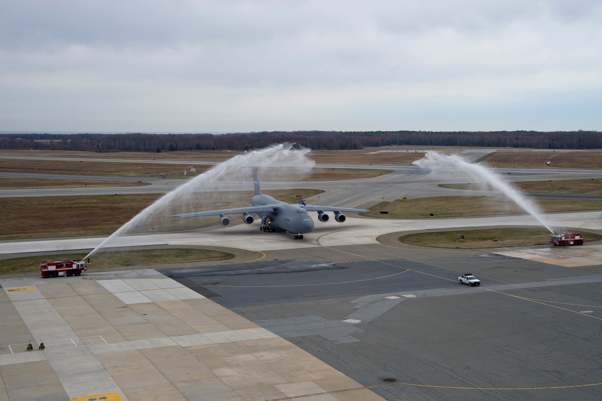 Fire trucks from the 436th Civil Engineer Squadron Fire Department give C-5M Super Galaxy 87-0040 and aircrew a customary spray-down as it pulls into a parking spot after its arrival to Dover Air Force Base, Del., on April 2, 2014. The addition of this aircraft makes DAFB the first base with a complete C-5M fleet. (U.S. Air Force photo/Staff Sgt. Elizabeth Morris)