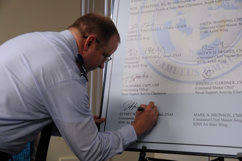 Col. Jeffrey DeVore, 628th Air Base Wing commander, signs his name on the 2014 Sexual Assault Proclamation April 1, 2014, to kick off Sexual Assault Awareness Month at Joint Base Charleston-Air Base. The commanders and command chiefs of the 315th Airlift Wing, 437th Airlift Wing, Naval Support Activity Charleston and 628th ABW each signed the document in a mutual show of support for victims of sexual assault and to affirm JB CHS’s stance against the crime. (U.S. Air Force photo by 1st Lt. Christopher Love) 