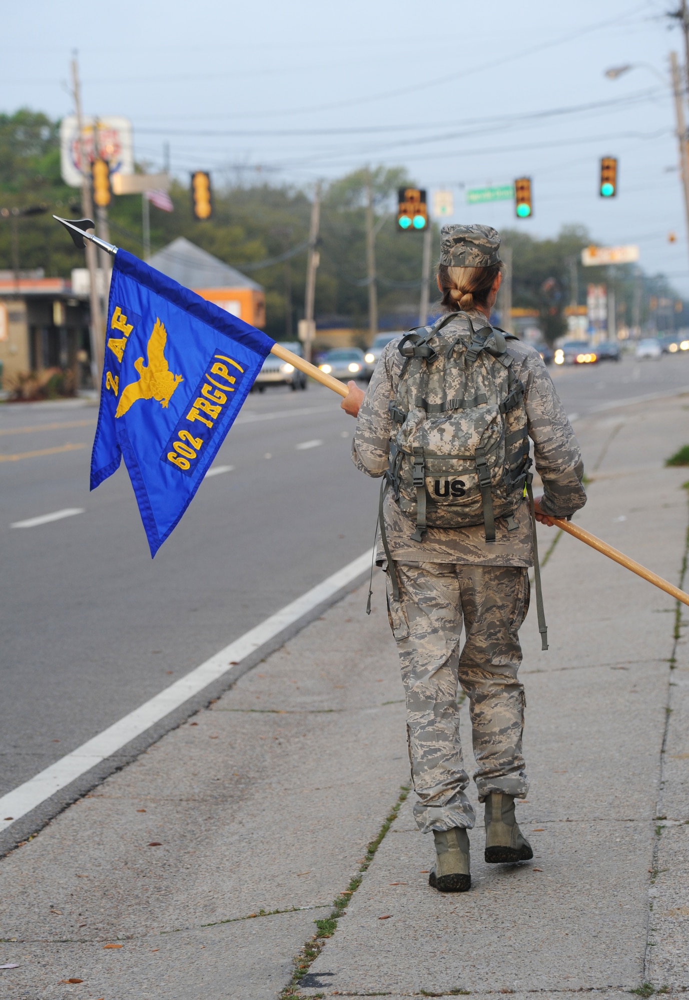 Col. Melanie Milburn, 602nd Training Group (Provisional) commander, carries a guidon and ruck sack down Pass Road as she participates in an 84-mile ruck march April 2, 2014,Biloxi, Miss.  The 2-day march, which began on Keesler and will end at Camp Shelby Army Post, Miss., took place to commemorate the 602nd TRG (P) mission in support of Joint Expeditionary Taskings and to their students who made the ultimate sacrifice. (U.S. Air Force photo by Kemberly Groue)