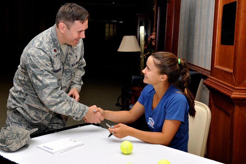 Maj. Daniel Thompson, 628th Air Base Wing Chaplain, gives a coin to professional tennis player Lauren Davis April 1, 2014, during a morale tour of Joint Base Charleston, S.C. The tour included signing autographs at the Charleston Club followed by a C-17A Globemaster III static tour. (U.S. Air Force photo/Staff Sgt. Renae Pittman)