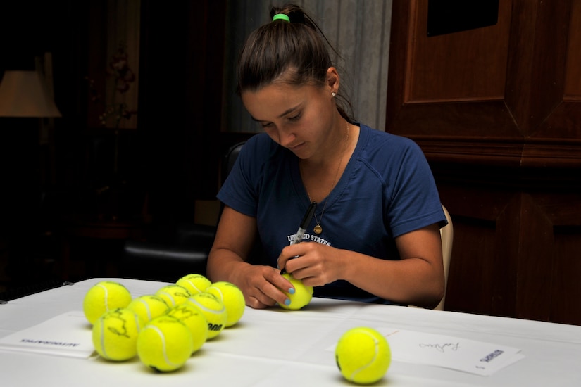 Professional tennis player Lauren Davis, signs tennis balls donated by the Heritage Trust Federal Credit Union April 1, 2014, during a base tour of Joint Base Charleston, S.C. The tour included signing autographs at the Charleston Club followed by a C-17A Globemaster III static tour. (U.S. Air Force photo/Staff Sgt. Renae Pittman)