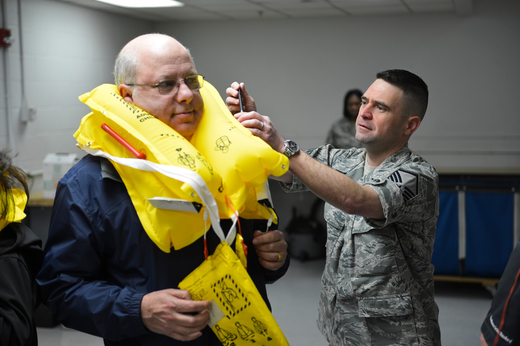 Master Sgt. John Hopper III, 62nd Operations Support Squadron aircrew flight equipment superintendent, assists Eric Kantor, Proforma Strategic Advantage vice president, with his personal flotation device during the aircrew flight equipment demonstration of the Fly-Away Civic Leader Tour March 28, 2014, at Joint Base Lewis-McChord, Wash. Following the demonstration, the civic leaders boarded a C-17 Globemaster III and flew to Travis Air Force Base, Calif. to continue the tour there. (U.S. Air Force photo by Staff Sgt. Russ Jackson)