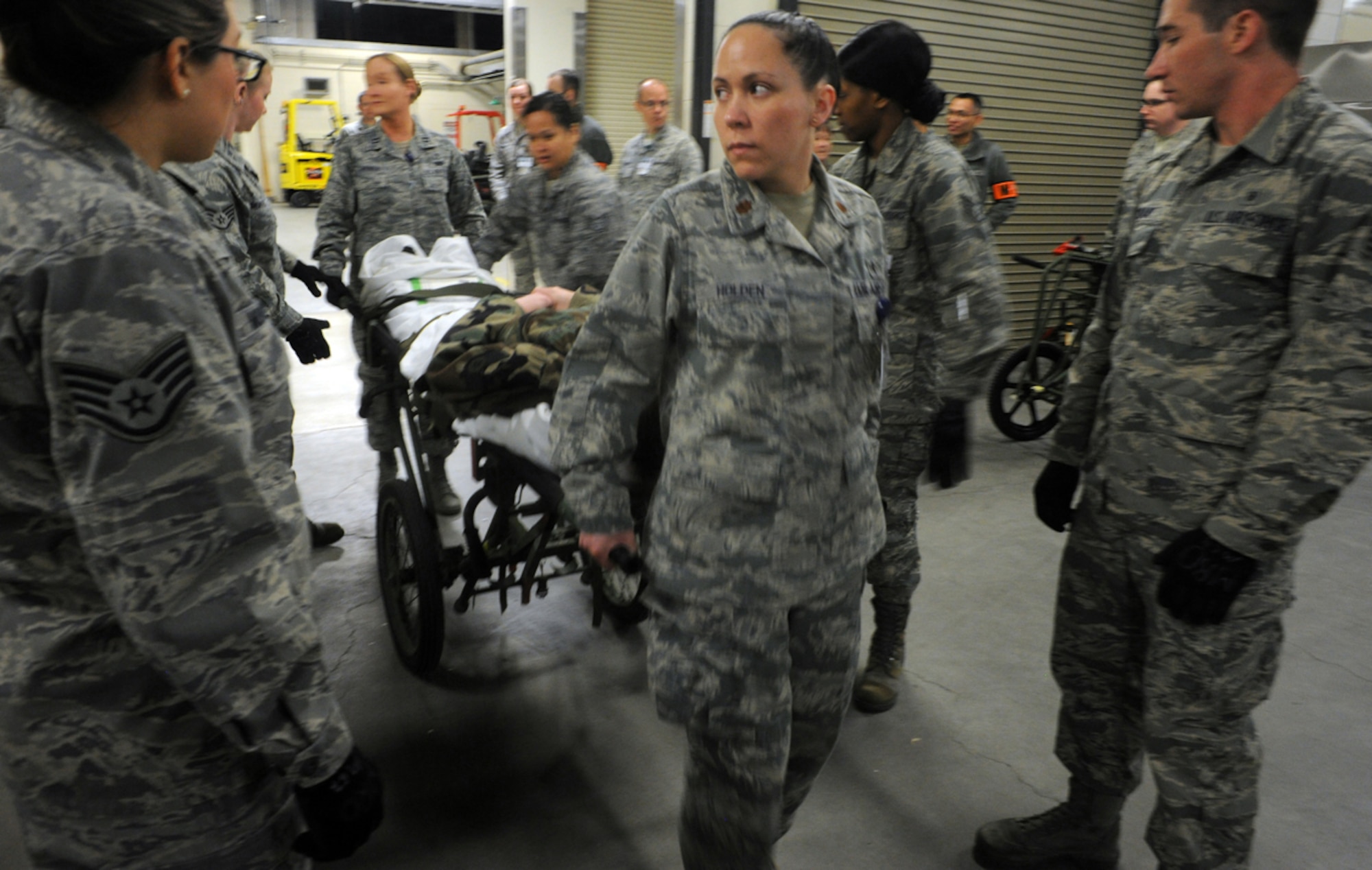 Air Force Maj. Sunny Holden, 673d Medical Group, leads a group of Airmen carrying a litter with a simulated natural disaster casualty during an evacuation drill as part of Mission Assurance Exercise 14-3 at Joint Base Elmendorf-Richardson, Alaska, March 31, 2014. MAE 14-3 is a JBER exercise testing the base’s ability to survive, operate and coordinate during a major natural disaster.   (U.S. Air Force photo/Justin Connaher)