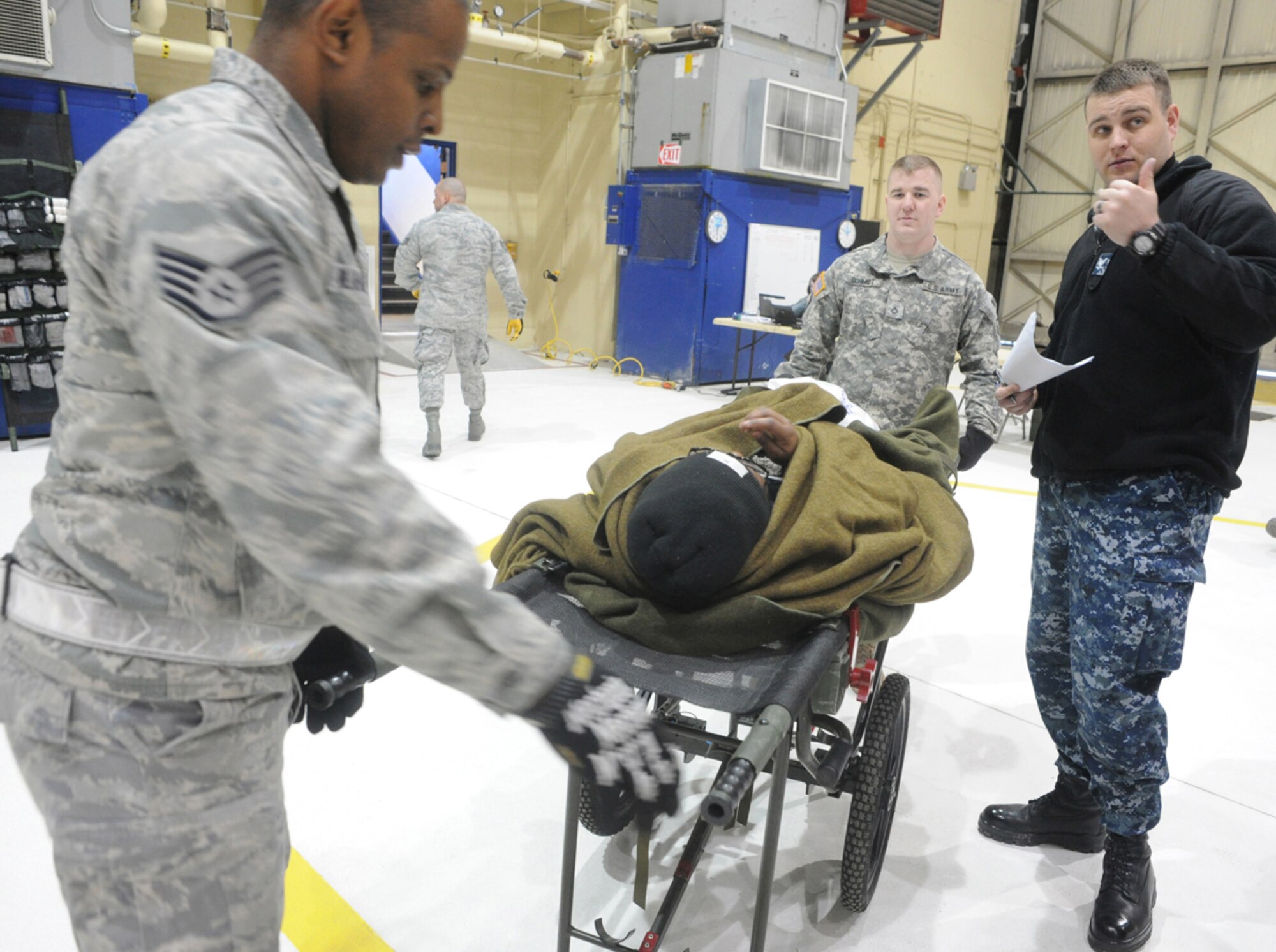 Air Force Staff Sgt. Jose Billar, left, 673d Medical Group, Army Pfc. David Schmidt, Headquarters and Headquarters Company 207th Aviation Regiment, and Navy Petty Officer 3rd Class Tracey Farris, Theater Patient Movement Requirement Center America, prepare a simulated natural disaster casualty for transport during an evacuation drill as part of Mission Assurance Exercise 14-3 at Joint Base Elmendorf-Richardson, Alaska, March 31, 2014. MAE 14-3 is a JBER exercise testing the base’s ability to survive, operate and coordinate during a major natural disaster.   (U.S. Air Force photo/Justin Connaher)