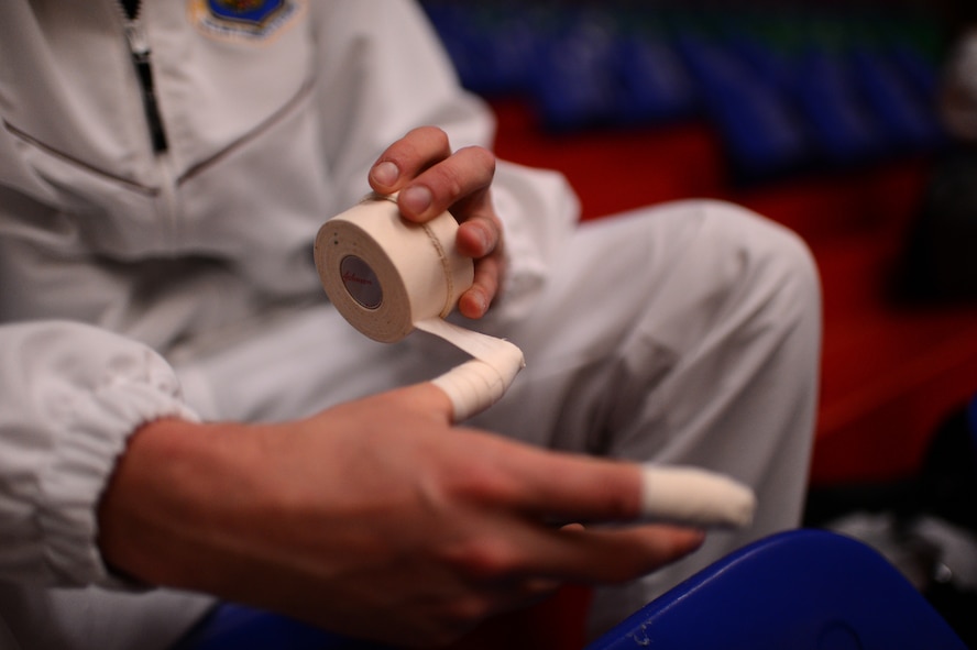 Stuart Sherman, U.S. Air Forces in Europe and Air Forces Africa men’s volleyball team outside hitter from Tuscon, Ariz., tapes his fingers before a Headquarters Allied Air Command Inter-Nation Sports Programme Volleyball Championship match in Amsterdam, March 26, 2014. Players tape their fingers to stiffen their joints while blocking a ball to avoid injury. (U.S. Air Force photo by Senior Airman Gustavo Castillo/Released)