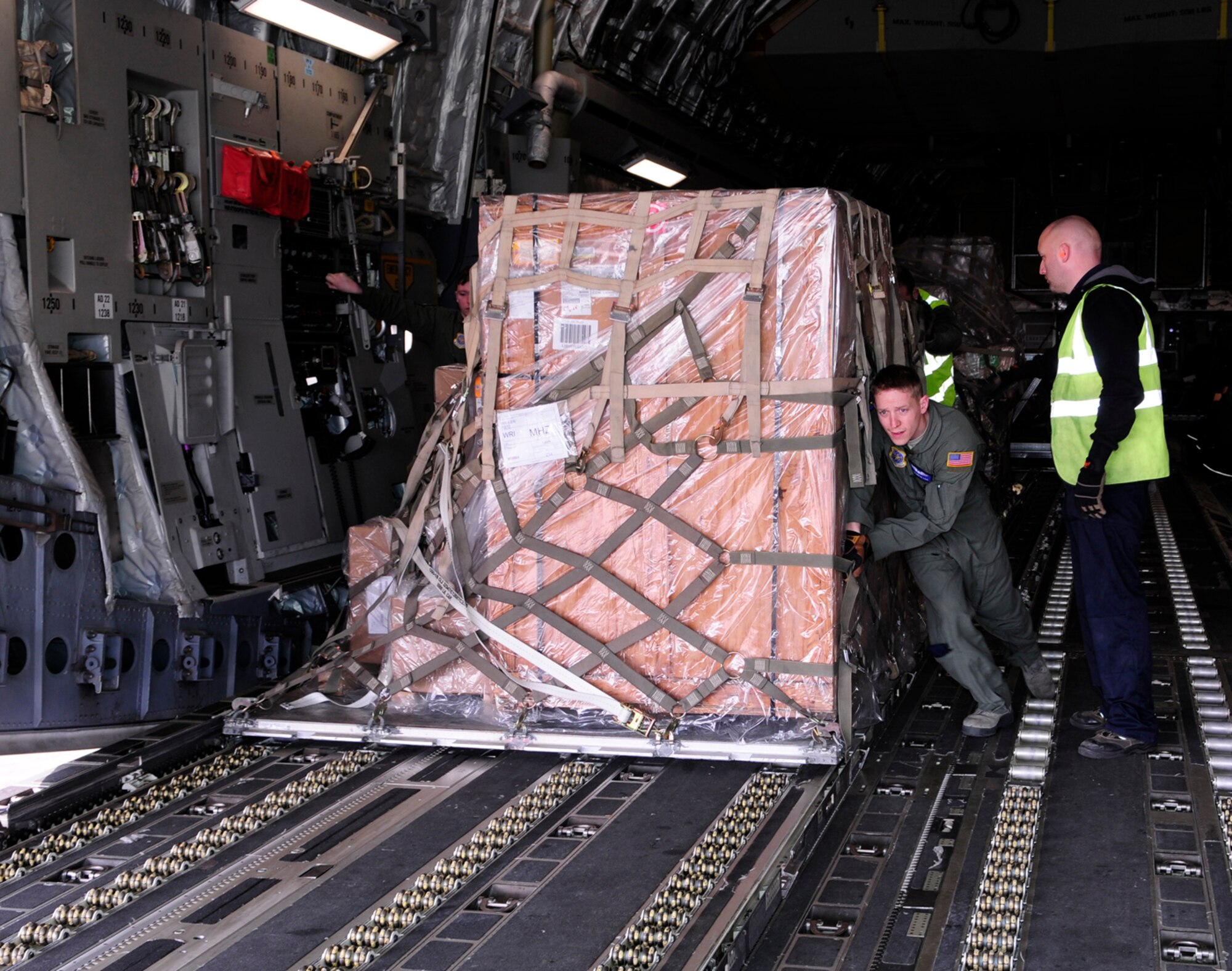 U.S. Air Force Senior Airman Brandon Cain, 6th Airlift Squadron Joint Base McGuire-Dix-Lakehurst, N.J., loadmaster from Stafford, Va., helps 727th Air Mobility Squadron Ministry of Defence employees unload a pallet of household goods from a C-17 Globemaster III from JB MDL March 12, 2014, on RAF Mildenhall, England. Aircraft from the U.S. regularly come through RAF Mildenhall, offloading and uploading cargo. (U.S. Air Force photo by Karen Abeyasekere/Released)