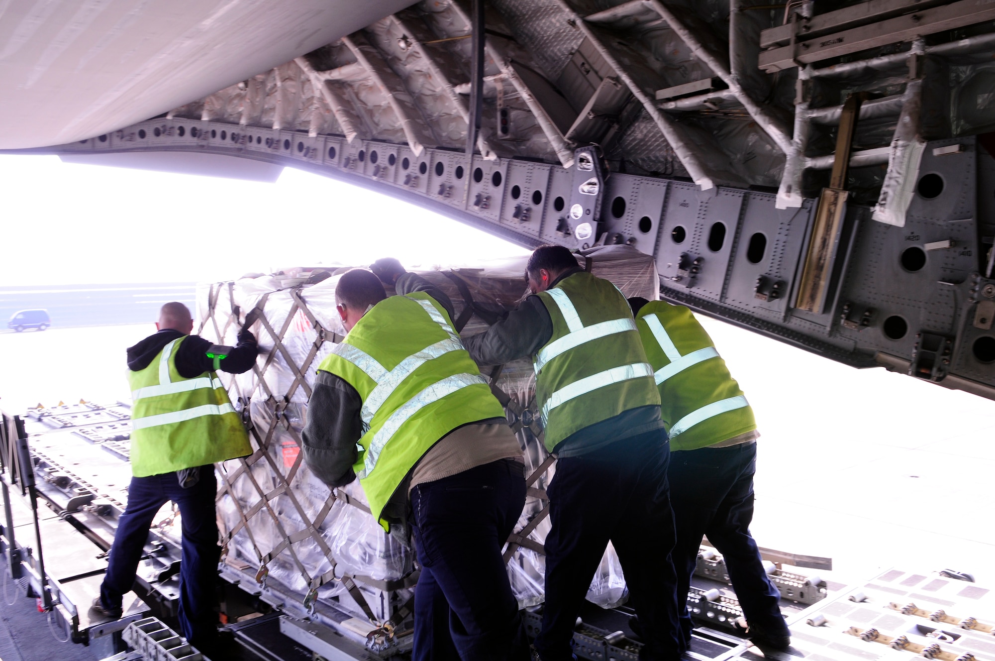 Ministry of Defence workers from the 727th Air Mobility Squadron Air Freight section move a pallet of household goods onto a K-loader from a C-17 Globemaster III March 12, 2014, on RAF Mildenhall, England. During 2013, the 727th AMS Air Freight section handled 3,900 tons of cargo from 3,800 aircraft missions. (U.S. Air Force photo by Karen Abeyasekere/Released)