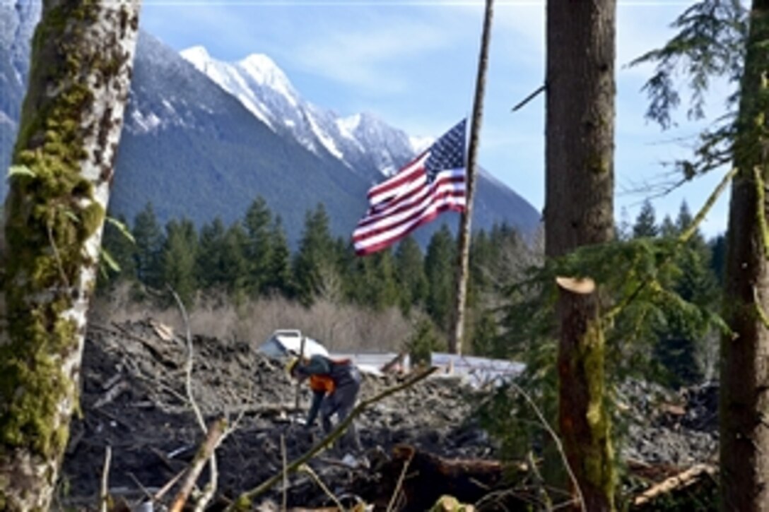 An American flag flies at half-staff in the rubble as the search continues for survivors in Oso, Wash., March 31, 2014, following a deadly mudslide. Troops and volunteers have assisted in the extensive search and rescue efforts.