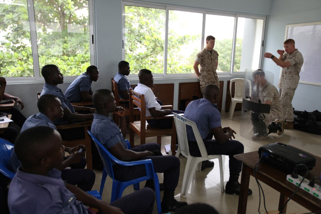 Captain Travis Posey, a team leader with Special-Purpose Marine Air-Ground Task Force Africa 14.1, demonstrates the proper way to coordinate shooting non-lethal ammunition over a riot-shield barrier during a week-long non-lethal weapons tactics course in Takoradi, Ghana, March 19. A team of Marines demonstrated techniques that focused on the force continuum, or how to escalate the use of force for a given scenario, non-lethal ammunition and vehicle arresting devices in order to promote and strengthen the ability to conduct good governance and development.
