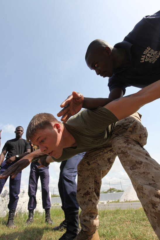 Lance Cpl. Dewayne Gregory, a Marine with Special-Purpose Marine Air-Ground Task Force Africa 14.1, plays to role of a violent rioter being detained by two Ghanaian sailors in Takoradi, Ghana, March 20. A team of Marines demonstrated tactics that focused on the force continuum, or how to escalate the use of force for a given scenario, non-lethal ammunition and vehicle arresting devices during a week-long non-lethal weapons tactics course in order to promote and strengthen the ability to conduct good governance and development.