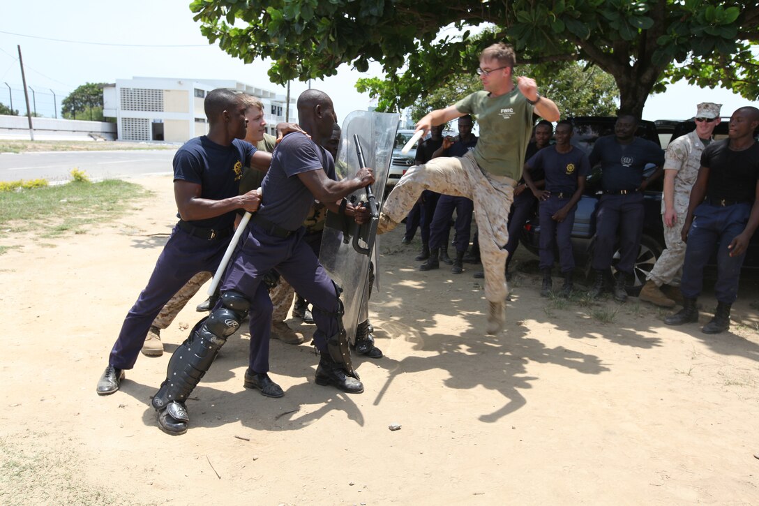 Lance Cpl. Sheridan Halfacre, a Marine with Special-Purpose Marine Air-Ground Task Force Africa 14.1, attempts to break through a riot-shield barrier held by a group of Ghanaian sailors during a week-long non-lethal weapons tactics course in Takoradi, Ghana, March 20. A team of Marines demonstrated tactics that focused on the force continuum, or how to escalate the use of force for a given scenario, non-lethal ammunition and vehicle arresting devices in order to promote and strengthen the ability to conduct good governance and development.
