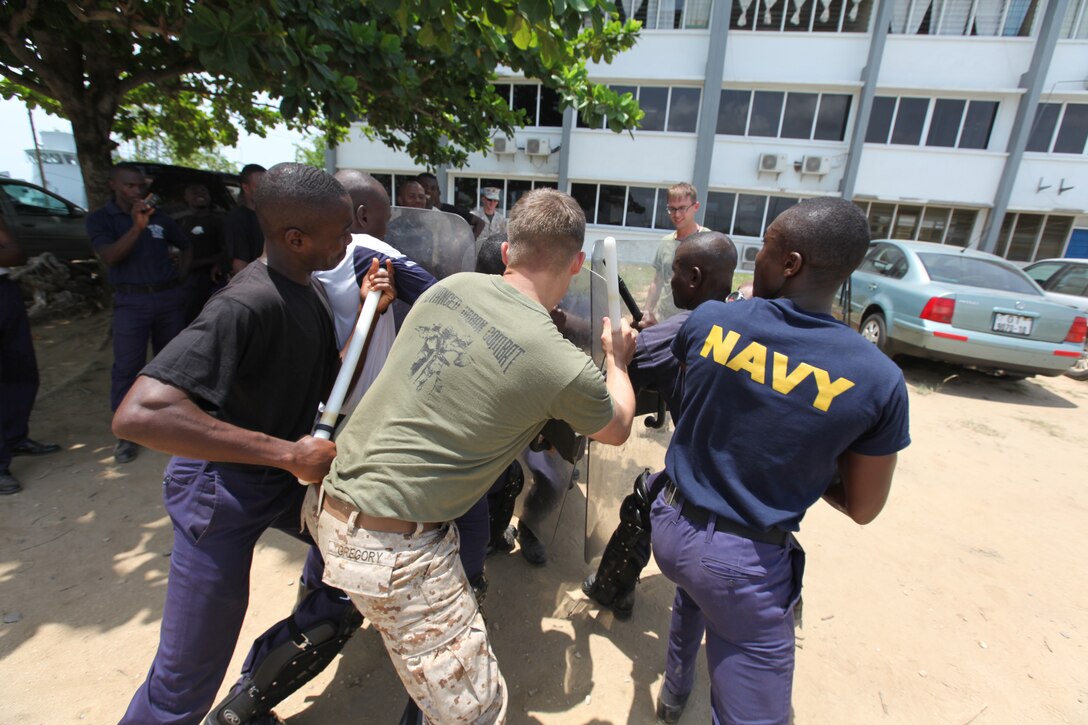 Lance Cpl. Dewayne Gregory (center), a Marine with Special-Purpose Marine Air-Ground Task Force Africa 14.1, reinforces a riot-shield barrier with a group of Ghanaian sailors during a week-long non-lethal weapons tactics course in Takoradi, Ghana, March 20. A team of Marines demonstrated tactics that focused on the force continuum, or how to escalate the use of force for a given scenario, non-lethal ammunition and vehicle arresting devices in order to promote and strengthen the ability to conduct good governance and development.
