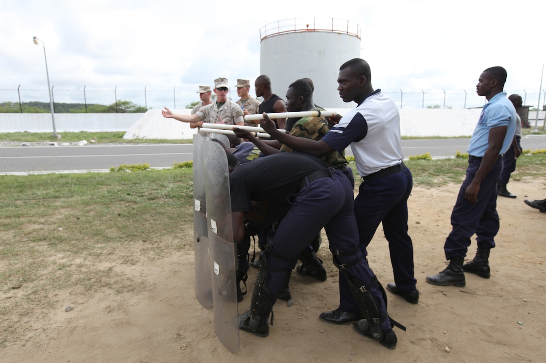 A group of Ghanaian sailors pose for a group photograph with two U.S. Marines from with Special-Purpose Marine Air-Ground Task Force Africa 14.1, March 21.  The team of Marines demonstrated tactics that focused on the force continuum, or how to escalate the use of force for a given scenario, non-lethal ammunition and vehicle arresting devices during a week-long course in order to promote and strengthen the ability to conduct good governance and development.