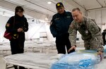 Staff Sgt. Ned Tri, right, Alaska Medical Station clinical noncommissioned officer-in-charge, explains to Maj. Ariunaa Chadraabal, left, and Col. Ulambayay Nyamkhuu, middle, representatives from Mongolia, the contents of a medical bag used during Exercises Alaska Shield and Vigilant Guard-Alaska 2014, March 28, 2014.