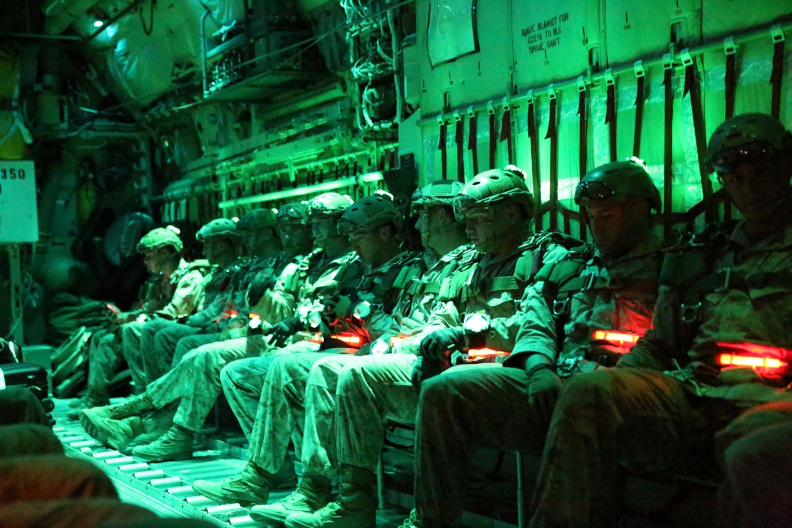 Marines with Bravo Company, 1st Reconnaissance Battalion, sit in a C-130 Hercules waiting for the command to parachute out of the plane during a double-bag static line course held in Parker, Ariz., March 24, 2014. A static line is a cord attached from one end of the aircraft to the other. When the Marine jumps from the plane, the line pulls the deployment bag out of the pack on the Marine’s back causing the parachute to inflate. The 24 Marines taking the course were evaluated on their jump form, their formation in the air and their landing. They conducted both day and night jumps and were required to jump a total of 12 times before they passed the course. (Photo by Lance Cpl. Christopher J. Moore/Released)