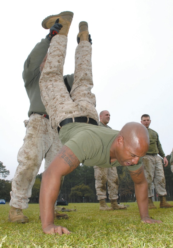 Gunnery Sgt. Quentin Green, packing specialist, Blount Island Command, Jacksonville, Fla., performs a buddy shoulder press while Maj. Miguel Toledano, company commander, Headquarters Company, BIC, holds his feet during the partner-series portion of the High Intensity Tactical Training level 1 training course, March 18-21. The training was held at Covella Pond aboard Marine Corps Logistics Base Albany.
