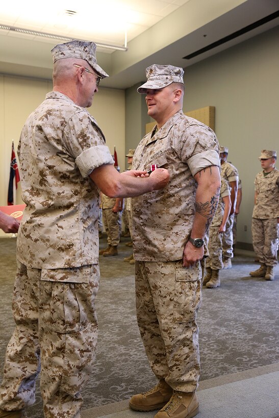 Retired Chief Warrant Officer Larry Earl Sr. pins a Meritorious Service Medal on his son's chest, Chief Warrant Officer Larry Earl Jr., during a retirement ceremony at Miller's Landing March 27, 2014, at Marine Corps Air Station Cherry Point, N.C. Earl Sr. was the presiding officer for his son when he enlisted in the Marine Corps and acted as the retiring officer 21 years later. Earl Jr. retired after serving as the 2nd Marine Aircraft Wing’s fuel’s officer. 