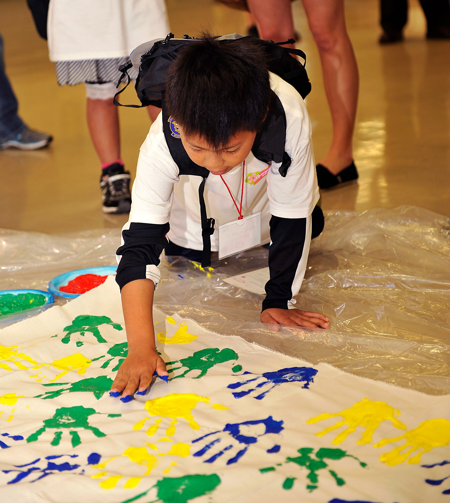A child from an Okinawan foster home, puts a hand print on a banner during Operation Sakura on Kadena Air Base, Japan, March 28, 2014. This is the second straight year that Kadena has conducted Operation Sakura. The children visited several facilities and engaged with American children their age during the visit. (U.S. Air Force photo by Naoto Anazawa)