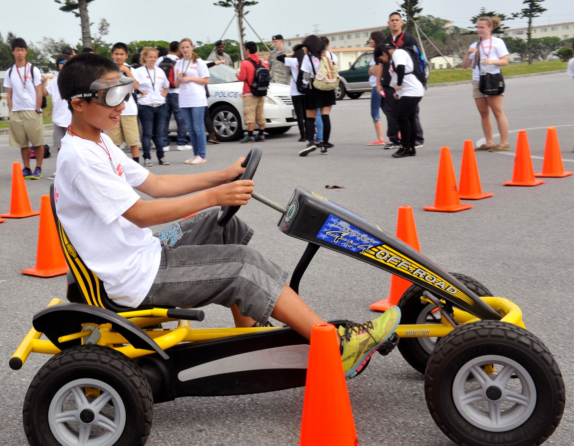 A child from an Okinawan foster home, tries a "Drink Buster" bike around cones while wearing drunk goggles during Operation Sakura on Kadena Air Base, Japan, March 28, 2014. Throughout the day, the children were given demonstrations by HH-60 Pave hawk pararescueman, military working dog handlers, and explosive ordinance disposal Airmen, and were participants during field events. (U.S. Air Force photo by Naoto Anazawa)