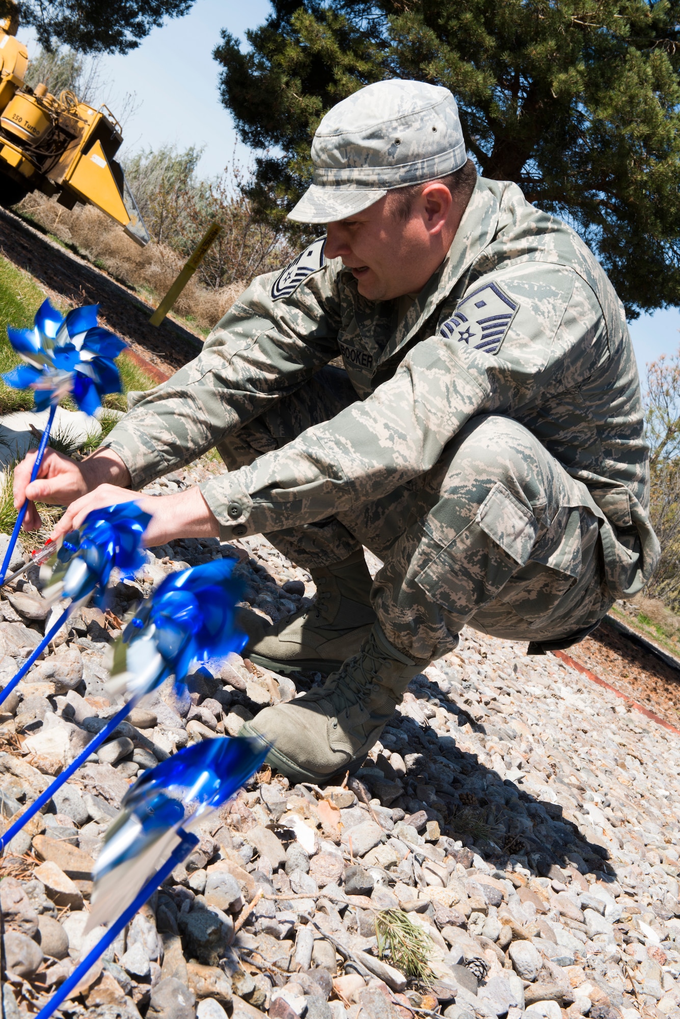 Master Sgt. Walter Booker, 366th Comptroller Squadron first sergeant, plants pinwheels at the front gate of Mountain Home Air Force Base, Idaho, April 3, 2014. Every year blue pinwheels are planted to bring awareness to child abuse. (U.S. photo by Airman 1st Class Malissa Lott/RELEASED)