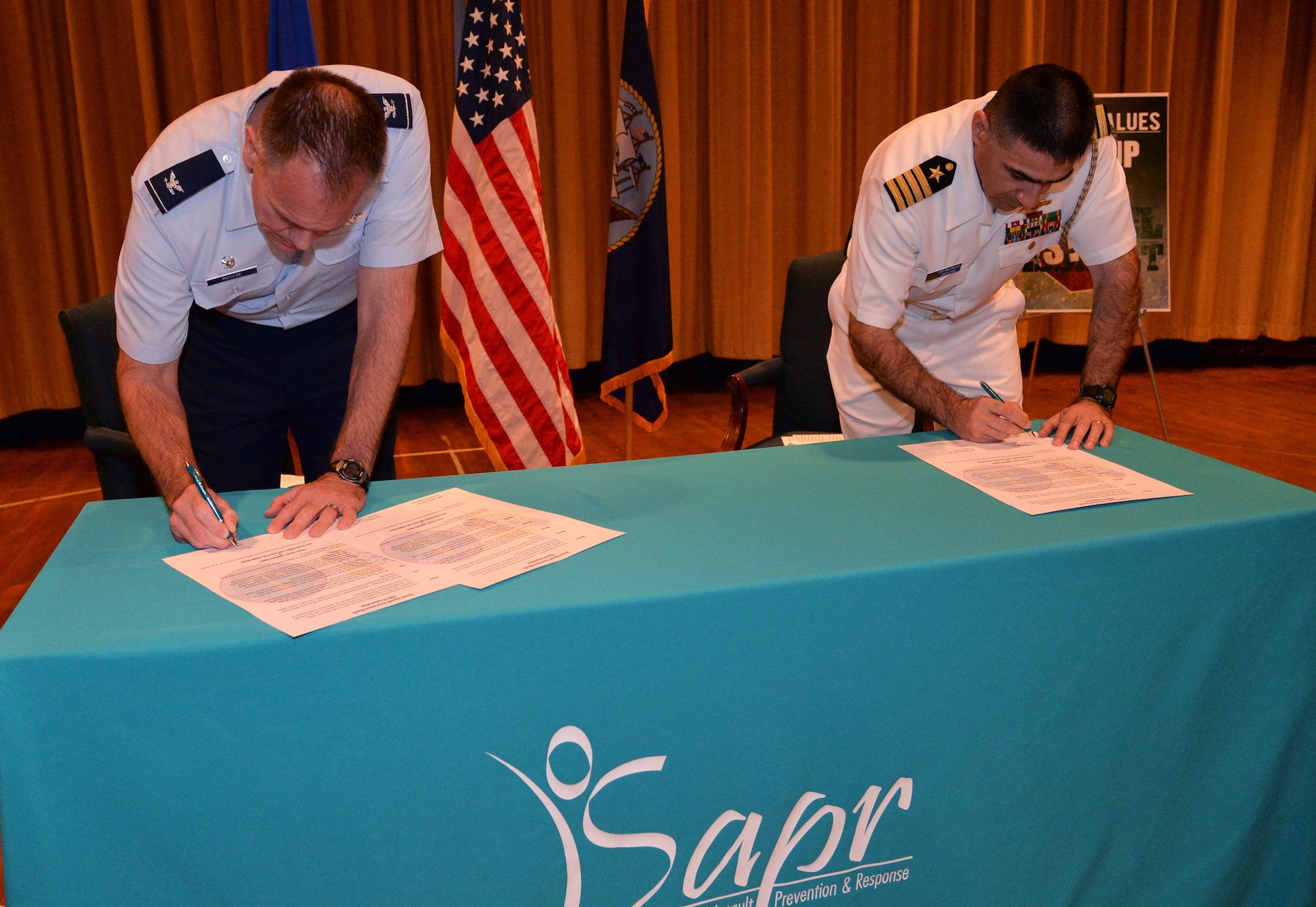 Col. Johnny Roscoe, 15th Wing commander, and Capt. Mark Manfredi, chief of staff, Navy Region Hawaii, sign a proclamation letter declaring April as Joint Base Pearl Harbor-Hickam Sexual Assault Awareness Month at Hickam Theater April 1, 2014. The proclamation signing event also included a presentation by Anne Munch, a nationally acclaimed prosecutor and sexual assault expert. (U.S. Air Force photo/Staff Sgt. Alexander Martinez)