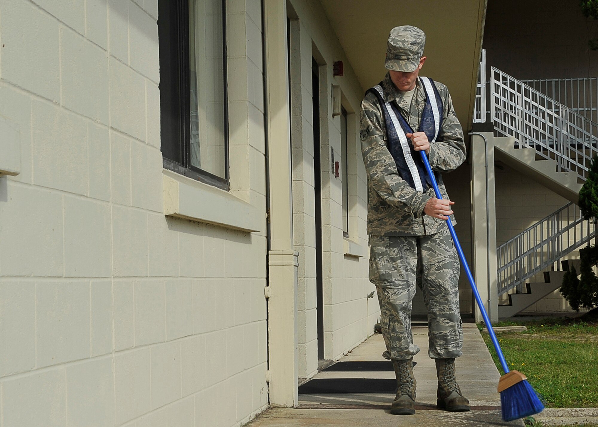 Airman 1st Class Ben Kubesh, 325th Maintenance Squadron airfield ground equipment, sweeps the sidewalk of a dormitory April 3. Kubesh is part of a bay orderly detail. (U.S. Air Force photo by Airman 1st Class Solomon Cook)    