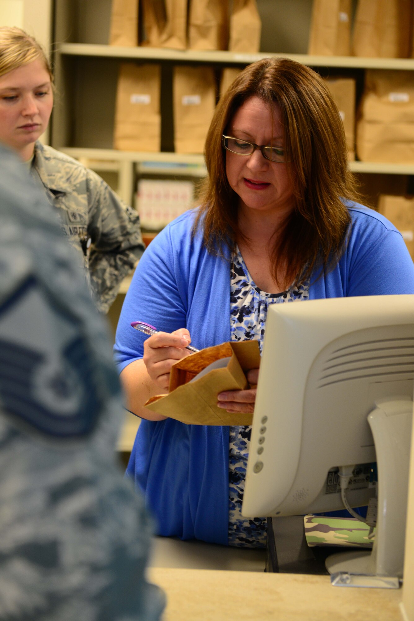 Michelle Acker, USAF Hospital Langley pharmacy volunteer, assists a patient at Langley Air Force Base, Va., April 2, 2014. The volunteer program is allows, active-duty Service members, spouses, dependents, retirees and other members of the community to volunteer within the hospital. (U.S. Air Force photo by Airman 1st Class Kimberly Nagle/Released)