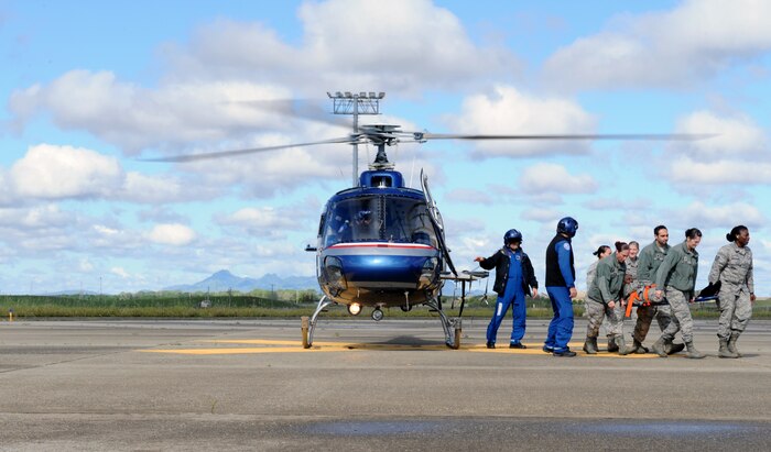 Beale Airmen and a flight crew from Enloe Emergency Services unload a patient from a helicopter during an exercise at Beale Air Force Base, Calif., April 2, 2014. Enloe Medical Center is located in Chico, Calif., and is available to respond during an emergency situation at Beale.  (U.S. Air Force photo by Airman 1st Class Bobby Cummings/Released)