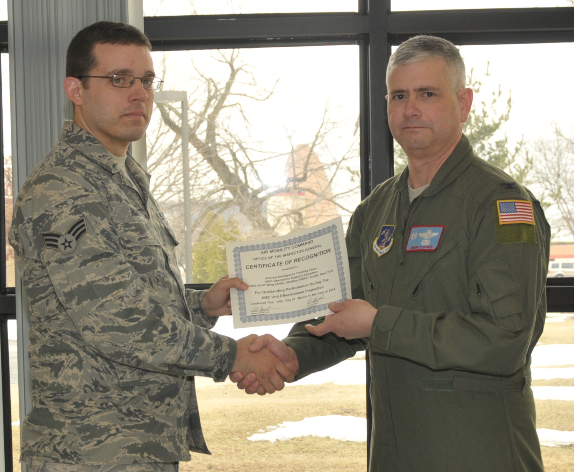 STRATTON AIR NATIONAL GUARD BASE, N.Y. -- Col. Shawn Clouthier (right), 109th Airlift Wing commander, presents Senior Airman Travis Inman with a certificate of recognition March 25, 2014, from Air Mobility Command for outstanding performance during the 109th AW's recent Unit Effectiveness Inspection. Inman and Staff Sgt. Joshua Hague (not pictured), 109th Operations Support Squadron, received team recognition as part of the Aircrew Intelligence Training Team. (Air National Guard photo by Master Sgt. William Gizara/Released)