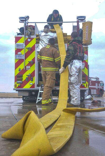 U.S Air Force Civil Engineer Squadron firefighters load a hose onto a fire truck at Whiteman Air Force Base, Mo., March 19, 2014. A hook must be properly placed to ensure rapid deployment for the next emergency. (U.S. Air Force photo by Airman 1st Class Keenan Berry/Released)