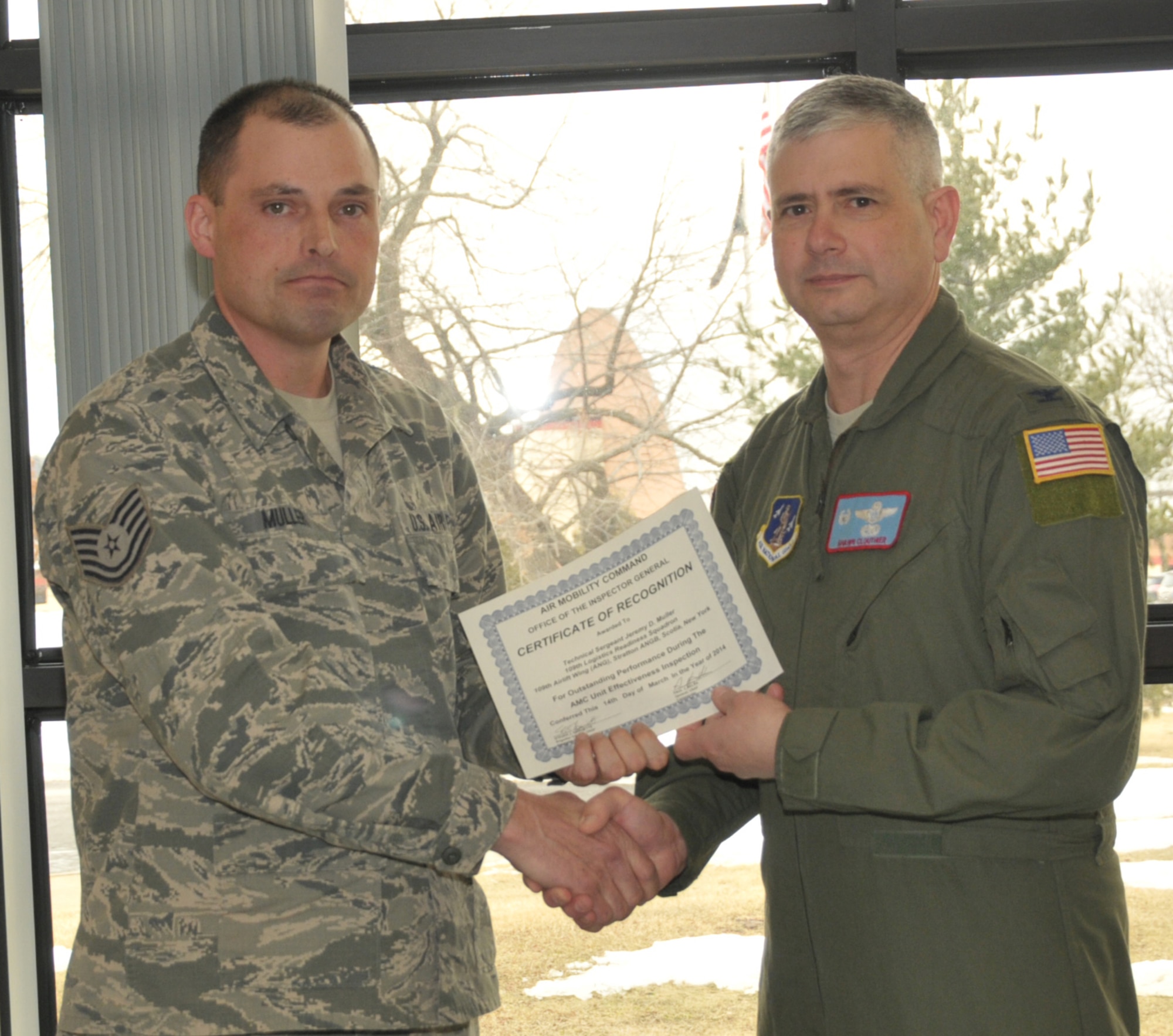 STRATTON AIR NATIONAL GUARD BASE -- Col. Shawn Clouthier (right), 109th Airlift Wing commander, presents Tech. Sgt. Jeremy Muller with a certificate of recognition March 25, 2014, from Air Mobility Command for outstanding performance during the 109th AW's recent Unit Effectiveness Inspection. Muller is assigned to the 109th Logistics Readiness Squadron. (Air National Guard photo by Master Sgt. William Gizara/Released)