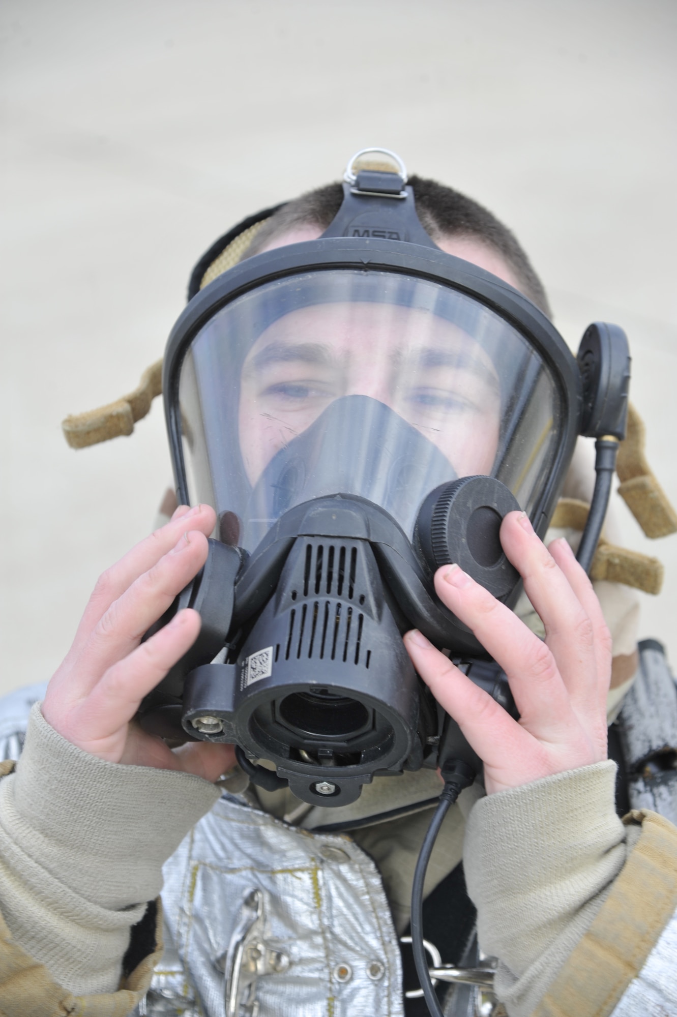 U.S. Air Force Staff Sgt. Elva Haywood, 509th Civil Engineer Squadron crew chief, dons a self-contained breathing apparatus mask at Whiteman Air Force Base, Mo., March 19, 2014. This mask allows firefighters to access hazardous environments and prevent respiratory problems. (U.S. Air Force photo by Airman 1st Class Keenan Berry/Released)