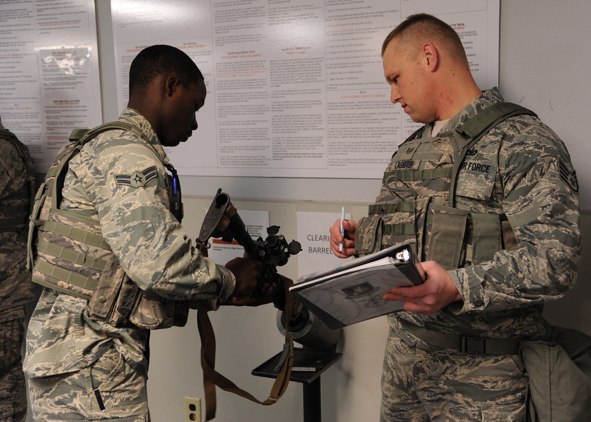Airman 1st Class Danallen Lee, 341st Security Forces Squadron member (left), goes through clearing procedures for his M-4 rifle with Staff Sgt. Justin Lassiter, 341st Missile Security Forces Squadron area supervisor, March 25. Lee will wear his flak vest, weapon, ammunition and radio – gear weighing nearly 30 pounds – for almost his entire shift. (U.S. Air Force photo/Senior Airman Cortney Paxton)