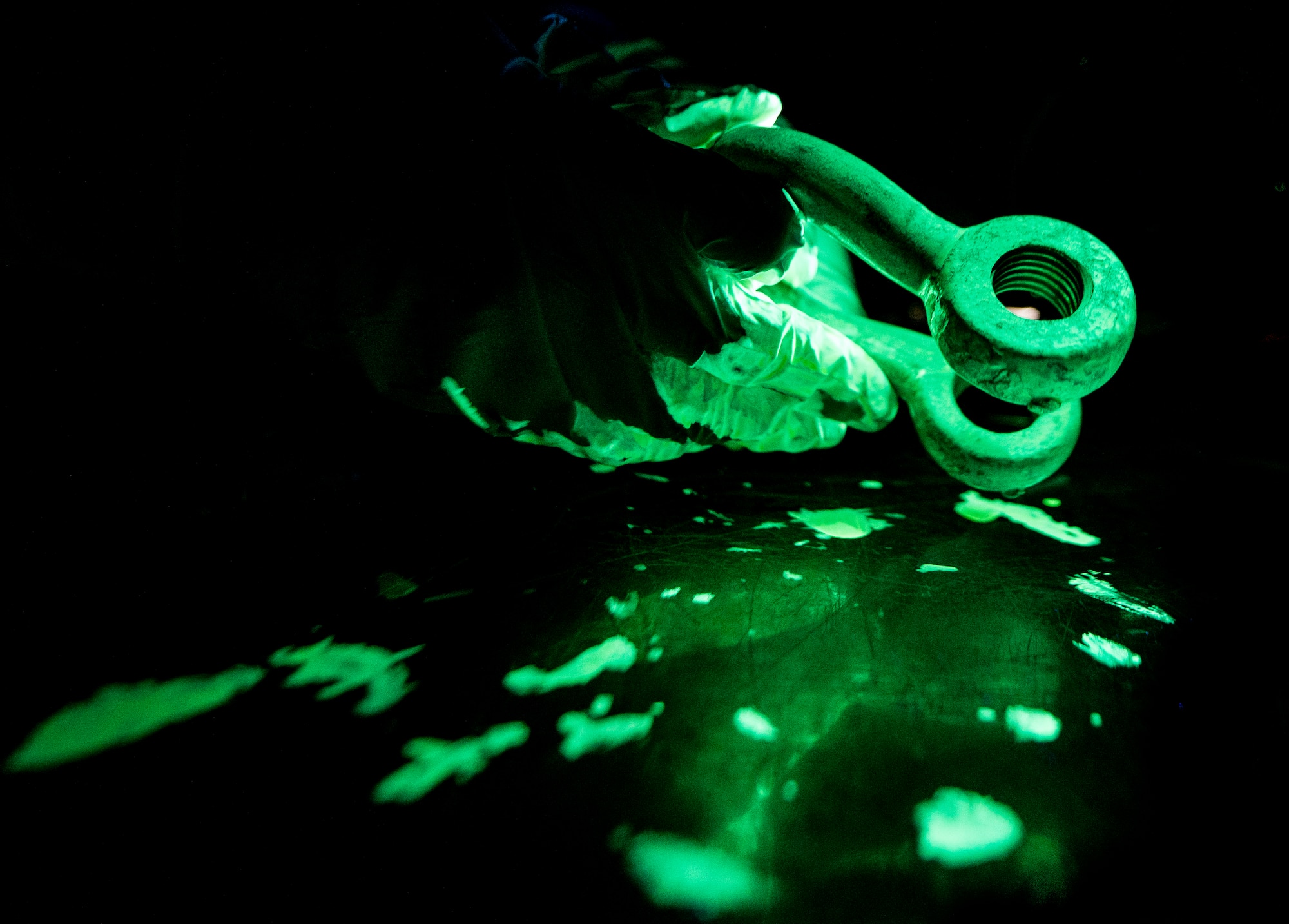 Airman 1st Class Henry Paulk, 437th Maintenance Squadron non-destructive inspector, wears gloves as he inspects a horseshoe shaped collar under ultraviolet lights while inspecting for cracks or defects in the aircraft part March 8, 2014, at Joint Base Charleston, S.C. The 437th MXS NDI shop inspects metal objects ranging from nuts and bolts, to large hooks and sheets of metal. (U.S. Air Force photo/Senior Airman Dennis Sloan)
