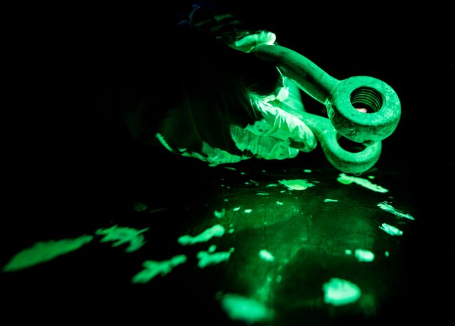 Airman 1st Class Henry Paulk, 437th Maintenance Squadron non-destructive inspector, wears gloves as he inspects a horseshoe shaped collar under ultraviolet lights while inspecting for cracks or defects in the aircraft part March 8, 2014, at Joint Base Charleston, S.C. The 437th MXS NDI shop inspects metal objects ranging from nuts and bolts, to large hooks and sheets of metal. (U.S. Air Force photo/Senior Airman Dennis Sloan)