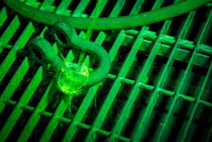 A dye, which glows under ultraviolet lights, is sprayed onto a horseshoe shaped collar as Airman 1st Class Henry Paulk, 437th Maintenance Squadron non-destructive inspector, inspects for cracks or defects March 8, 2014, at Joint Base Charleston, S.C. The 437th MXS NDI shop inspects metal objects ranging from nuts and bolts, to large hooks and sheets of metal. (U.S. Air Force photo/Senior Airman Dennis Sloan)