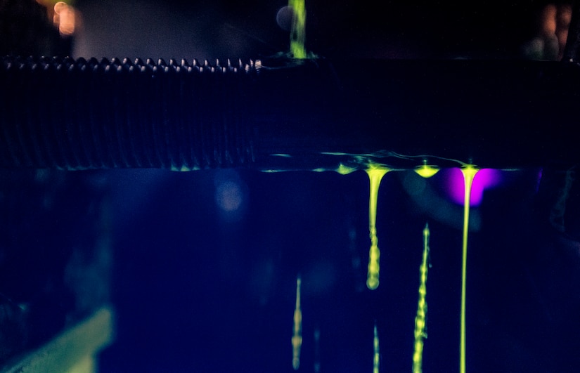 A dye, which glows under ultraviolet lights, pours off of a large bolt as Tech. Sgt. Ryan Michalec, 437th Maintenance Squadron non-destructive inspector, inspects for cracks or defects March 8, 2014, at Joint Base Charleston, S.C. The 437th MXS NDI shop inspects metal objects ranging from nuts and bolts, to large hooks and sheets of metal. (U.S. Air Force photo/Senior Airman Dennis Sloan)