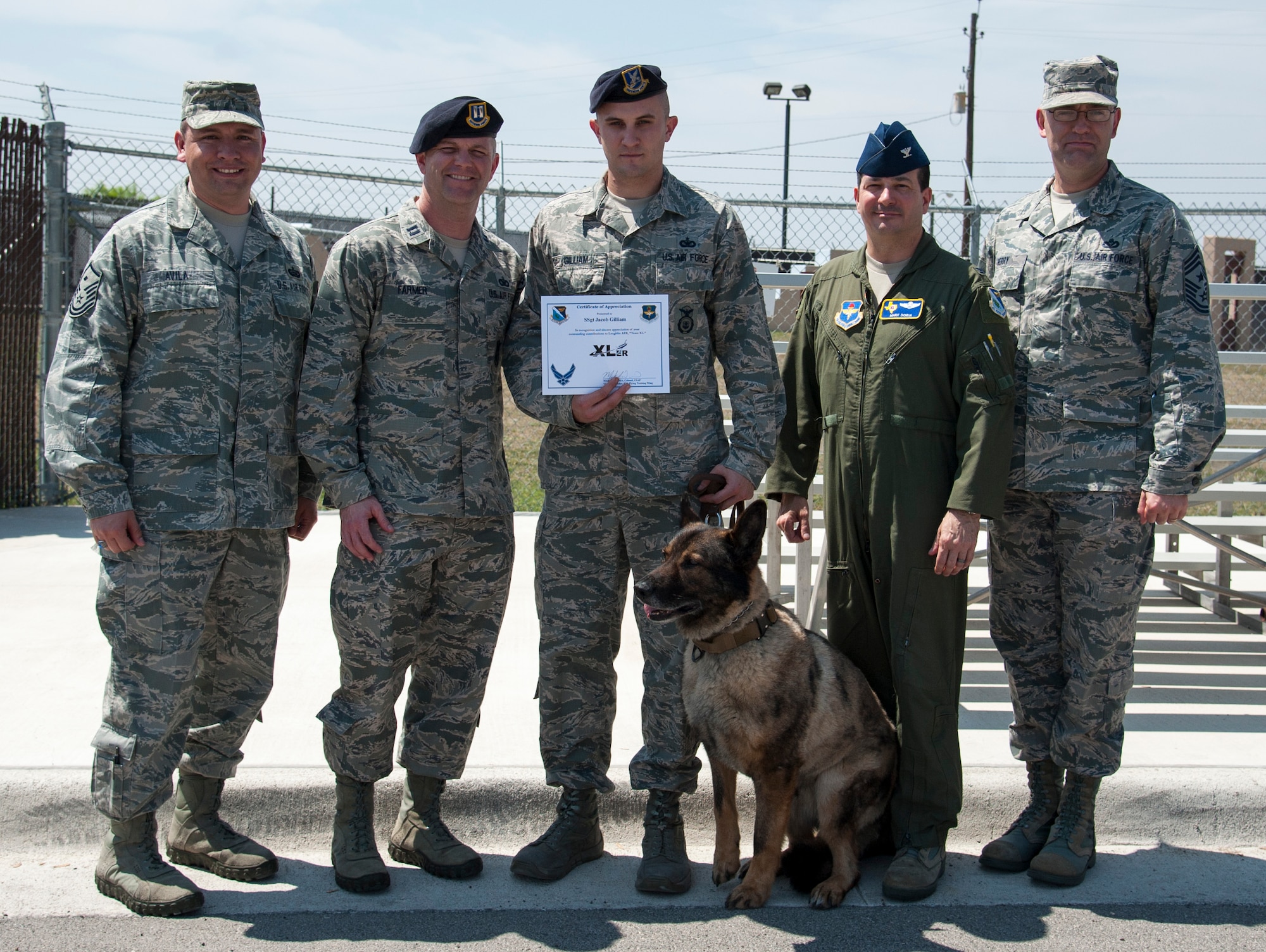 From left, Master Sgt. Abraham Avila, 47th Security Forces Squadron first sergeant; Capt. John Farmer, 47th SFS commander; Staff Sgt. Jacob Gilliam, 47th SFS Military Working Dog handler; Beny, 47th SFS military working dog; Col. Mark Doria, 47th Flying Training Wing vice commander; and Chief Master Sgt. Garry Berry, 47th FTW command chief, pose for a photo after Gilliam was presented the XLer of the week award here April 2, 2014. The XLer is a weekly award chosen by wing leadership and given to those who consistently make outstanding contributions to their unit and Laughlin. (U.S. Air Force photo/Airman 1st Class Jimmie D. Pike/Released)