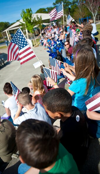 Children wave flags and pinwheels during the proclamation-signing ceremeony for the month of the military child and child abuse prevention at the community park on Hurlburt Field, Fla., April 2, 2014. The ceremony recognized military children and the National Blue Ribbon campaign to prevent child abuse. (U.S Air Force photo/Senior Airman Krystal M. Garrett) 
