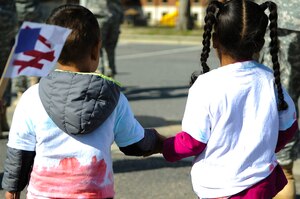 Two children hold hands during a Month of the Military Child march at Fort Eustis, Va., April 1, 2014. The Pershing Child Development Center scheduled more events throughout April to celebrate military children. (U.S. Air Force photo by Senior Airman Austin Harvill/Released) 