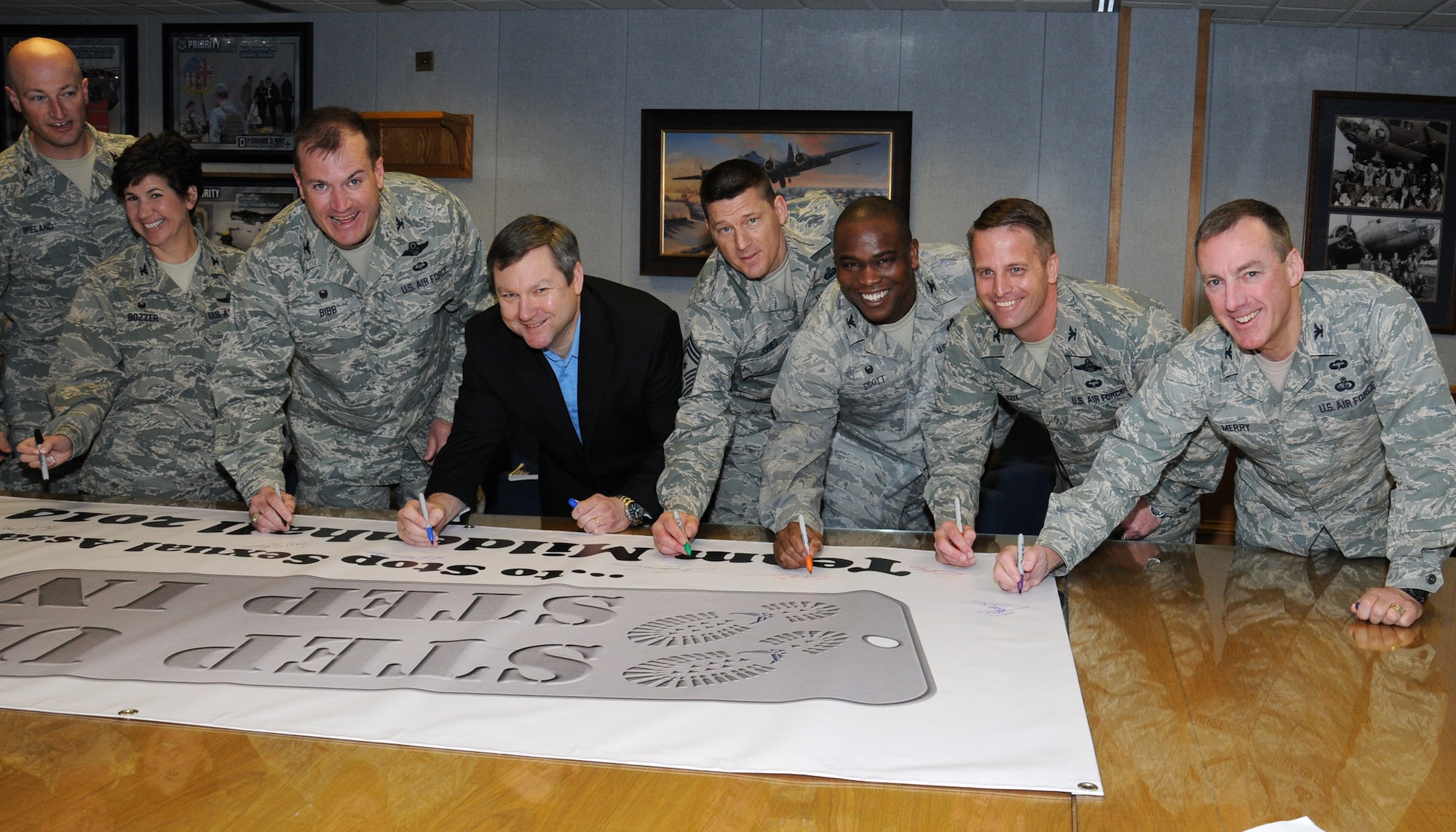 David Spencer, center, 100th Air Refueling Wing Sexual Assault Prevention and Response coordinator, leads Team Mildenhall leaders in signing a banner April 2, 2014, on RAF Mildenhall, England. Signing the banner is one way Team Mildenhall members can to show their support for stopping sexual assault. As part of Sexual Assault Awareness Month, there will be a SAPR down day on April 18. (U.S. Air Force photo by Gina Randall/Released)