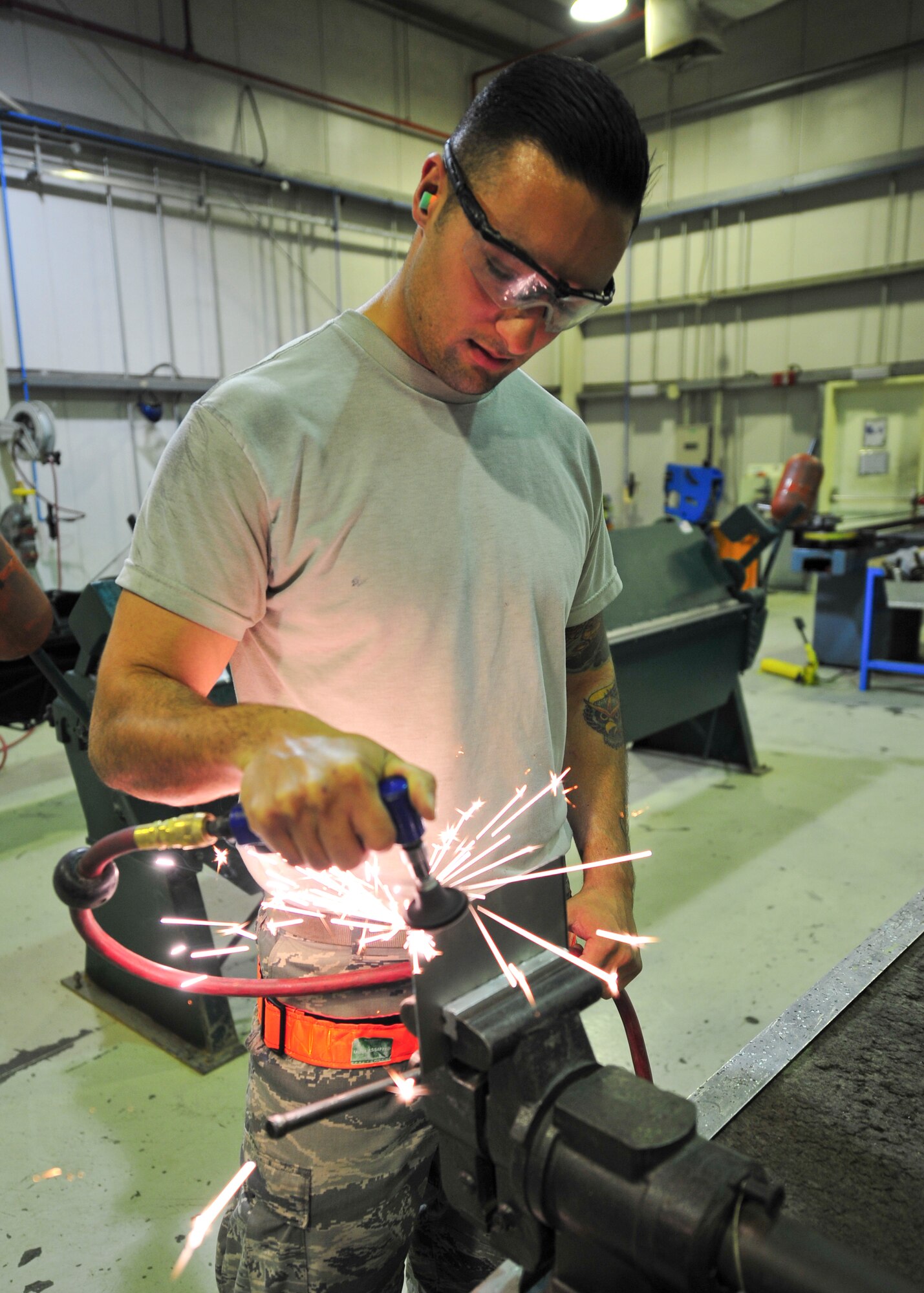 Air Force Senior Airman Cody Borden, 380th Expeditionary Maintenance Squadron aircraft structural maintenance journeyman, uses a pneumatic sander to file a sheet metal patch at an undisclosed location in Southwest Asia, April 1, 2014. Borden is a native of Newport News, Va., and is deployed from Tinker Air Force Base, Okla. (U.S. Air Force photo by Staff Sgt. Michael Means/Released)